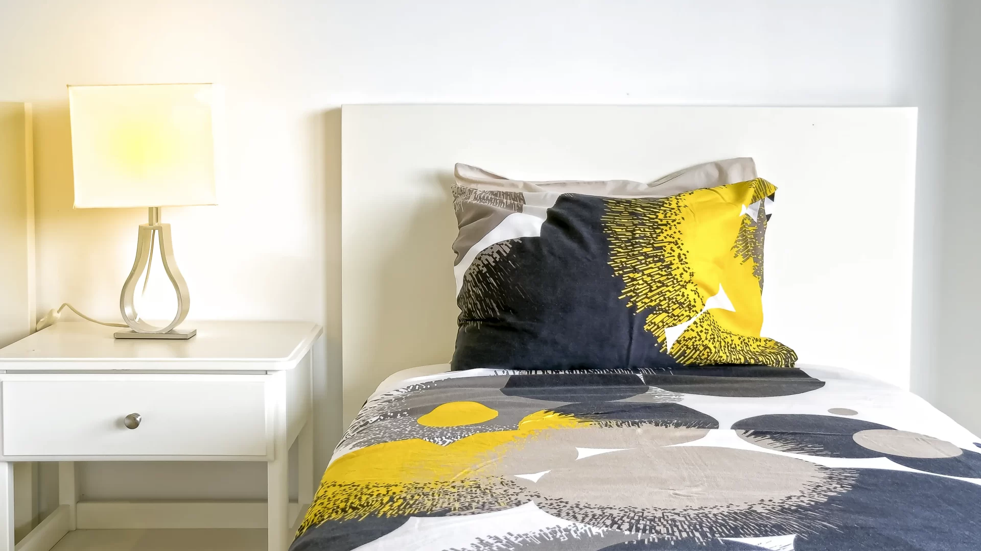 Single bed with a night table and lamp at Las Olas residential